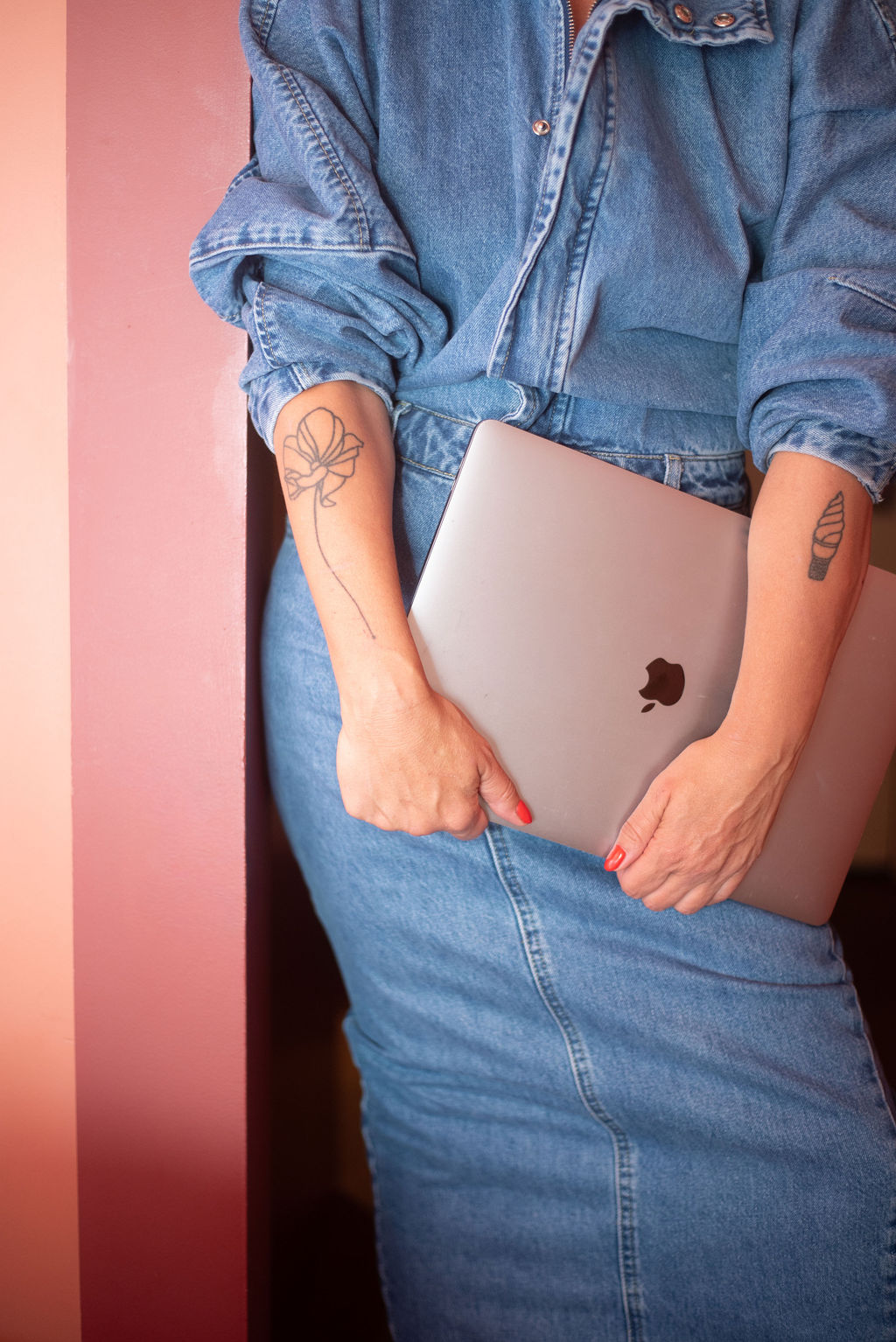 Steph holding a laptop against a pink wall