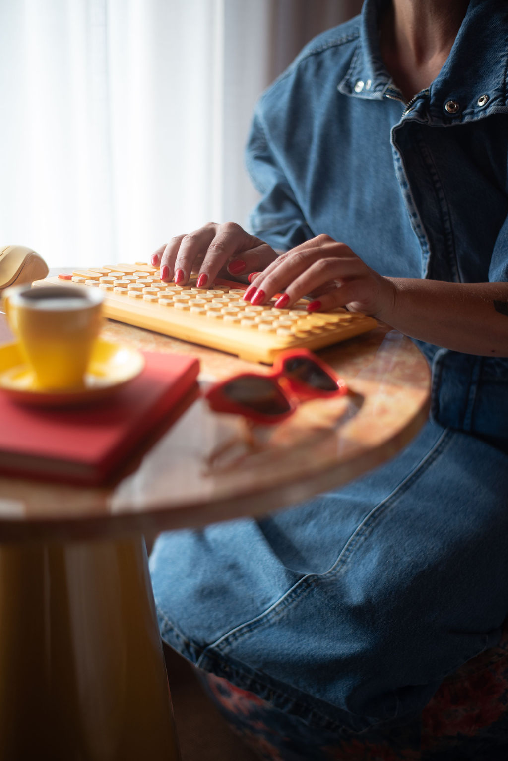 Steph typing at a yellow keyboard beside a cup and notebook